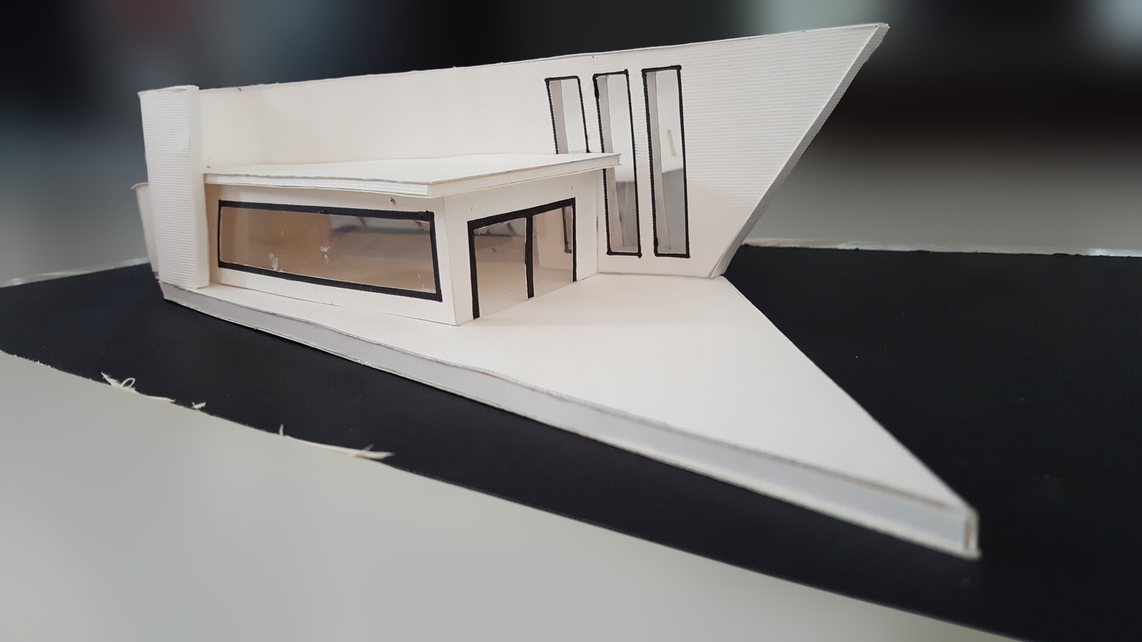 White architectural model with a cantilevered roof and narrow columns