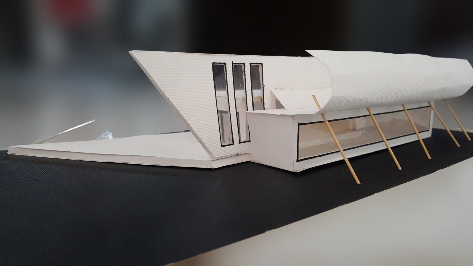 Side view of a white building model with elevated terrace supports
