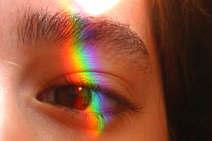 Close-up of an eye crossed by rainbow light