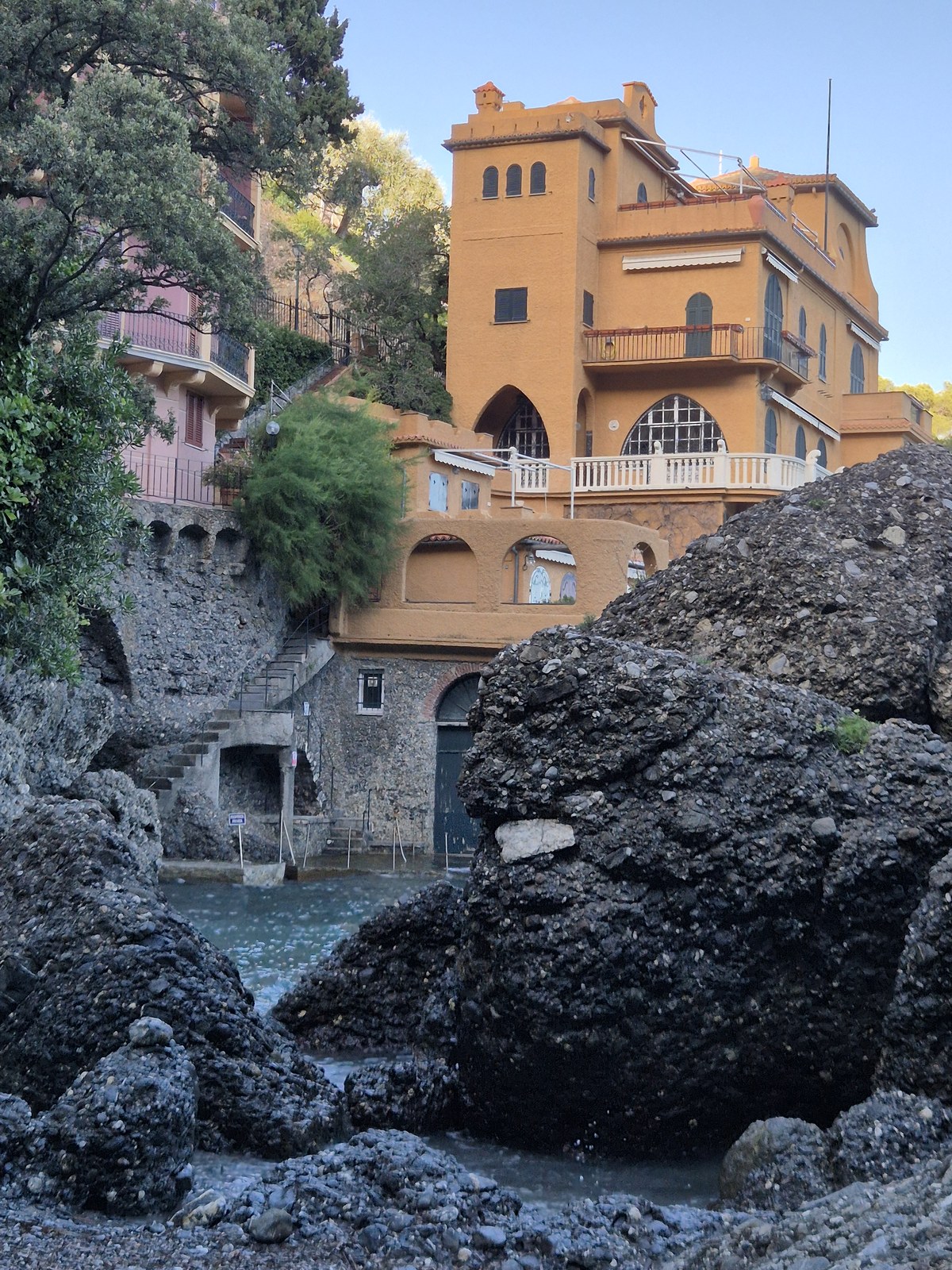 Ochre building above rocks beside a hillside